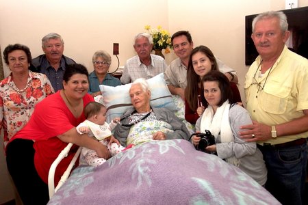 Kinders, kleinkinders, agter-kleinkinders en agter-agter-kleinkind staan bankvas agter Tannie Rens Fourie tydens haar 96ste verjaardag op 25 April vanjaar